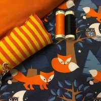 Biologische tricot met oranje vossen op een blauwe achtergrond. Gecobineerd met kaneeloranje tricot en geel oranje gestreepte boordstof